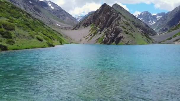 Un dron vuela sobre un lago de montaña turquesa — Vídeos de Stock