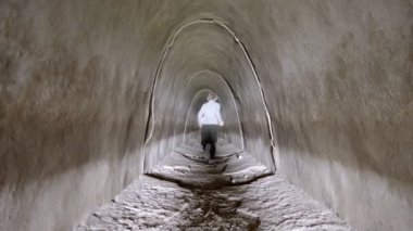 Bir çocuk beton tünelden ışığa doğru koşuyor.