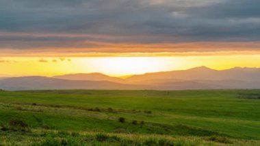 Alçak bulutlarla kaplı dağlık bir bölgede muhteşem bir günbatımı manzarası