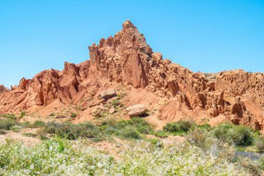 Keskin Dağ, Peri Masalı Kanyonu Kırgızistan, Skazka Kanyonu 'nda bulutsuz ve çöl bitkisi olmayan parlak mavi gökyüzüne karşı kırmızı turuncu taştan yapılmış bir kayadır..