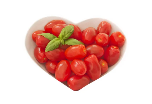 Baby plum tomates in a heart shaped bowl — Stock Photo, Image