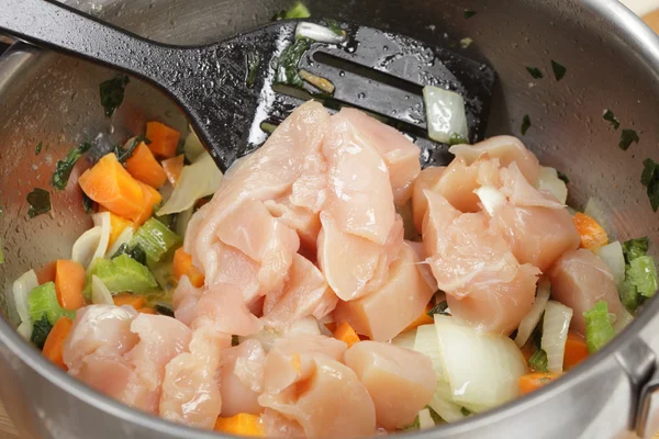 Adding raw chicken cubes to risotto — Stock Photo, Image