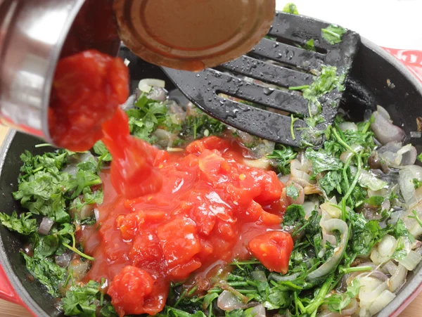 Adicionando tomates à salsa e cebola — Fotografia de Stock