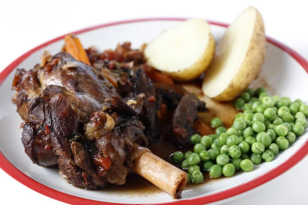 Lamb shank meal with peas and potato — Stock Photo, Image