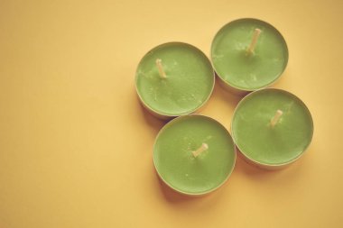 Sarı masada dört tane yeni yeşil mum. Üst görünüm.