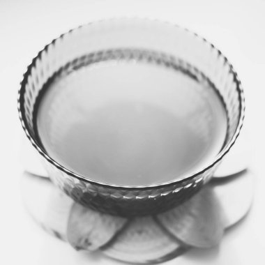 Ahşap tahtada ve pencere pervazında içki olan cam kâse. BW fotoğrafı.