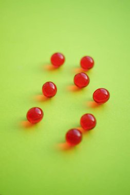 Canlı yeşil bir masada yuvarlak kırmızı vitaminler.