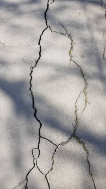 Güneşli bir günde asfalttan yapılmış eski bir yol yüzeyinin deseni..