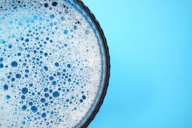 Mavi bir masada köpüklü su ve kabarcıklarla dolu cam kase, boşluğu kopyala.