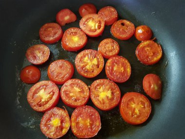 the process of frying tomato slices in a pan