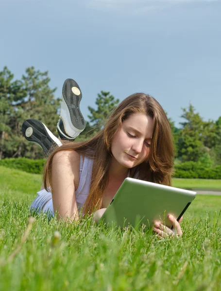 Chica joven usando una tableta en el parque — Foto de Stock