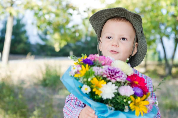 Niedlicher kleiner Junge mit Blumenstrauß — Stockfoto