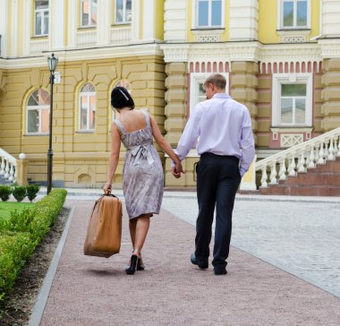 Couple walking with woman carrying luggage clipart