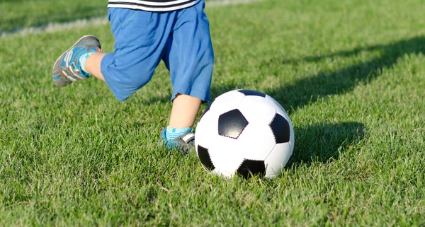 Criança chutando uma bola de futebol — Fotografia de Stock