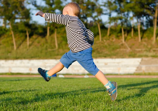 Kleine jongen midair schoppen van een bal — Stockfoto