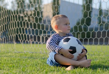 Burnunun üzerinde bir futbol topu ile küçük çocuk