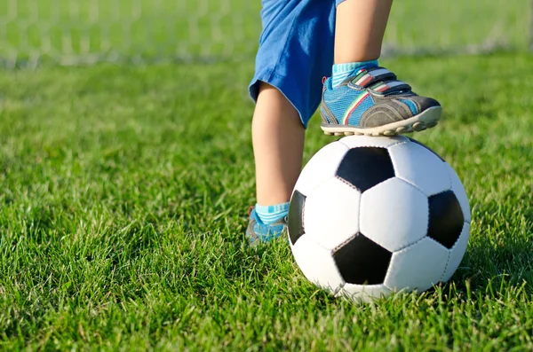 Garçon avec son pied sur un ballon de football — Photo