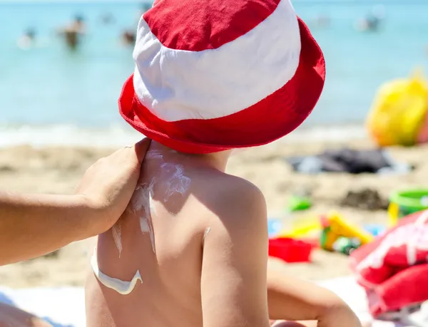 Jonge jongen met zonnebrandcrème aangebracht — Stockfoto