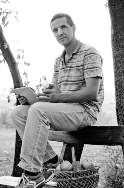 Hombre usando una tableta y comiendo una manzana — Foto de Stock