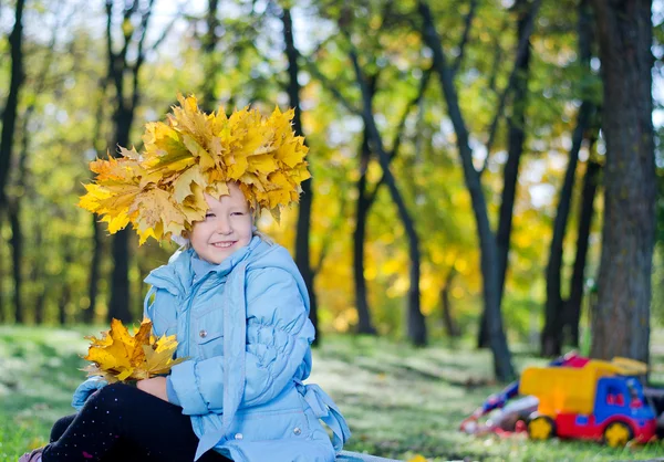 Smiling young girl with hat of autumn leaves — Stock Photo, Image