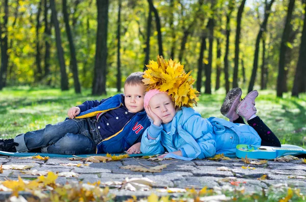 Bambini piccoli sdraiati vicini in un parco autunnale — Foto Stock