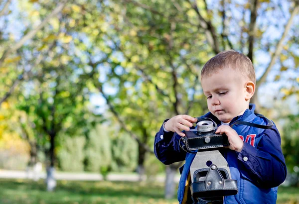 Mały chłopiec bawi się pewien starodawny aparat fotograficzny — Zdjęcie stockowe