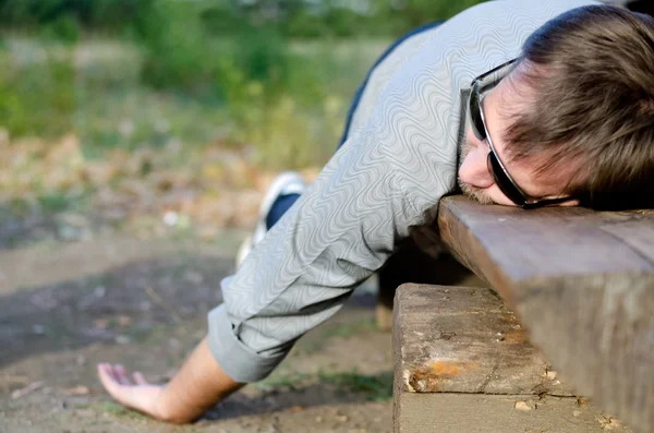 Homem exausto dormindo em um banco — Fotografia de Stock