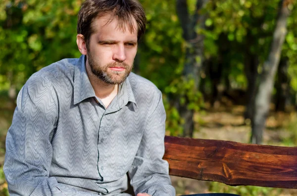 Uomo seduto a pensare su una panchina di legno — Foto Stock