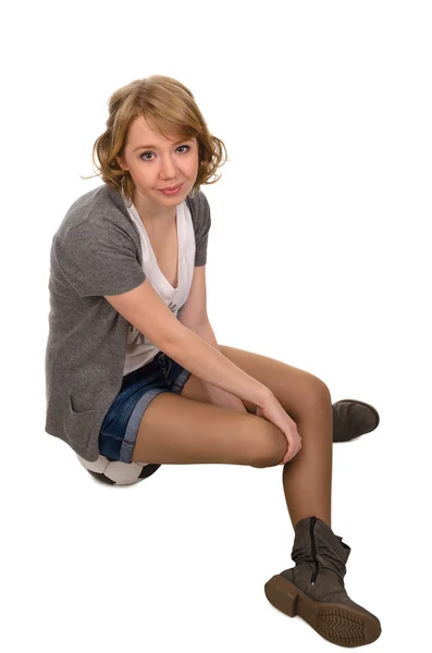 Pretty young blonde woman sitting on a football — Stock Photo, Image