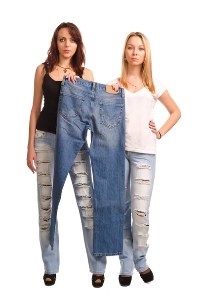 Two young women holding up a pair of jeans — Stock Photo, Image