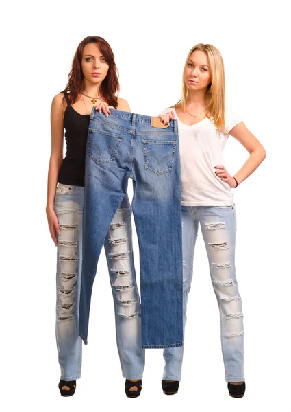 Two young women holding up a pair of jeans — Stock Photo, Image
