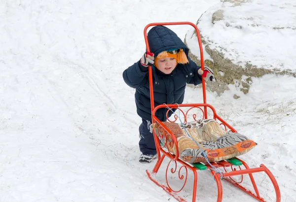 Little boy pushing his sled in snow — Stock Photo, Image