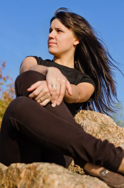 Attraktive Frau sitzt auf einem Felsen — Stockfoto