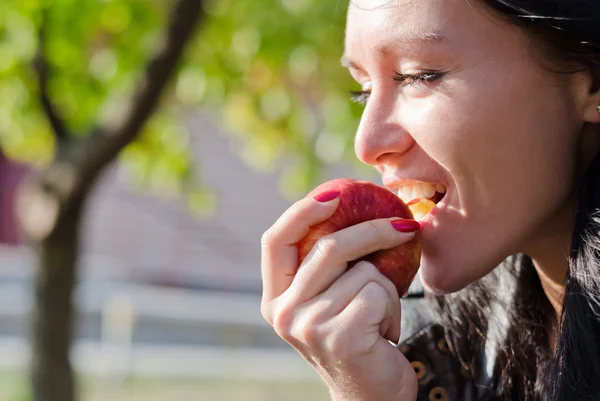 Vrouw bijten in een rode appel — Stockfoto