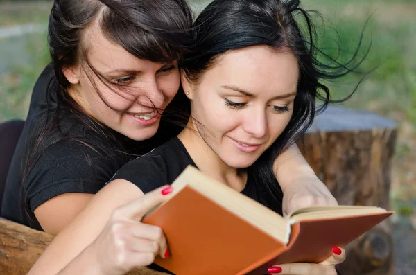 Two close woman friends enjoying a book — Stock Photo, Image