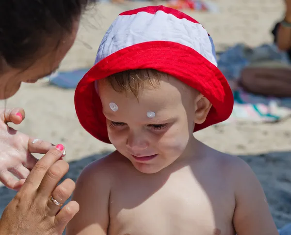 Mother applying sunscreen on her son — Stock Photo, Image