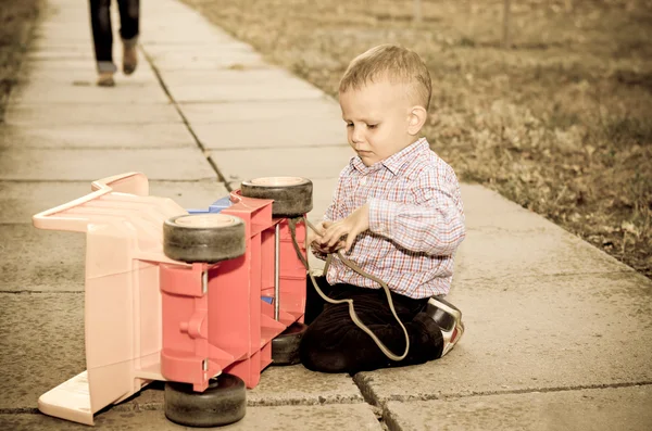 Piccolo ragazzo che gioca con un camion di plastica — Foto Stock