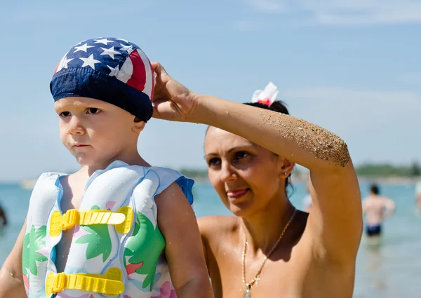 Mami, upevnění její synové plavání čepice — Stock fotografie