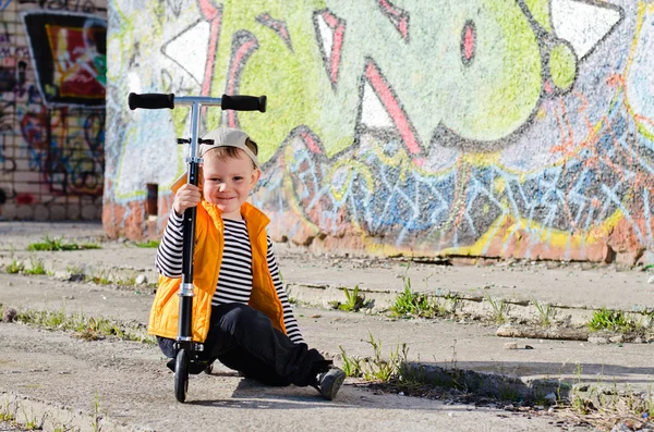Netter kleiner Junge sitzt auf seinem Roller — Stockfoto