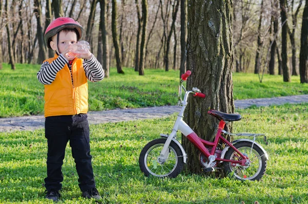 Thirsty little boy drinking water while out riding — Stock Photo, Image