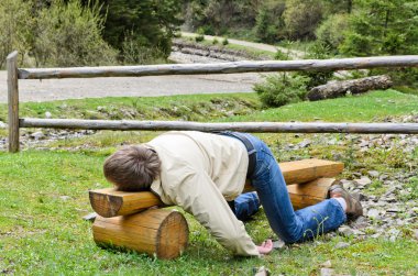 Young blond man deeply sleeping on a bench outdoor clipart