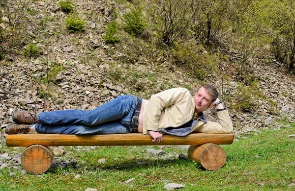 Young blond man laying on his side on a bench — Stock Photo, Image