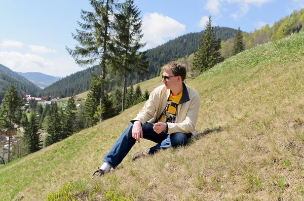 Muž sedí na strmém horském svahu — Stock fotografie