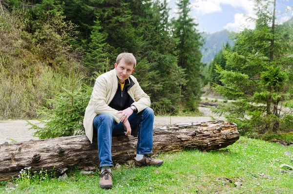 Freundlicher Mann sitzt auf einem Baumstamm — Stockfoto