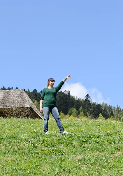 Frau steht auf einer grünen Wiese und zeigt — Stockfoto