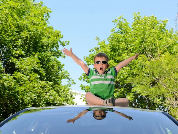 Boy on the roof of car — Stock Photo, Image