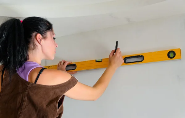 Woman using a spirit level while renovating — Stock Photo, Image