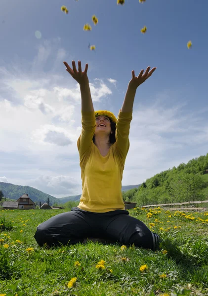 Jovem mulher joga flores amarelas no ar — Fotografia de Stock