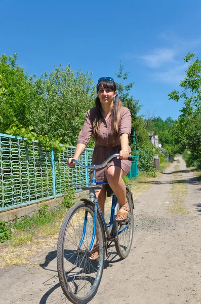 Woman riding a bicycle down a rural lane — Stock Photo, Image