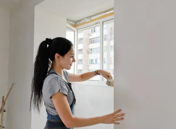 Vrouw schilderij een muur met een penseel — Stockfoto